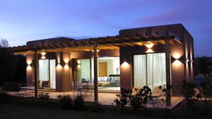 A modern house with a covered patio, large windows, and a well-lit interior. - Villa Jardins d'Isa (Marrakech)