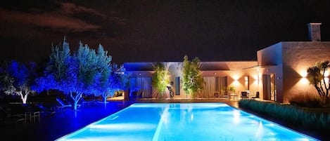 Una piscina al aire libre, sombrillas, sillones reclinables de piscina