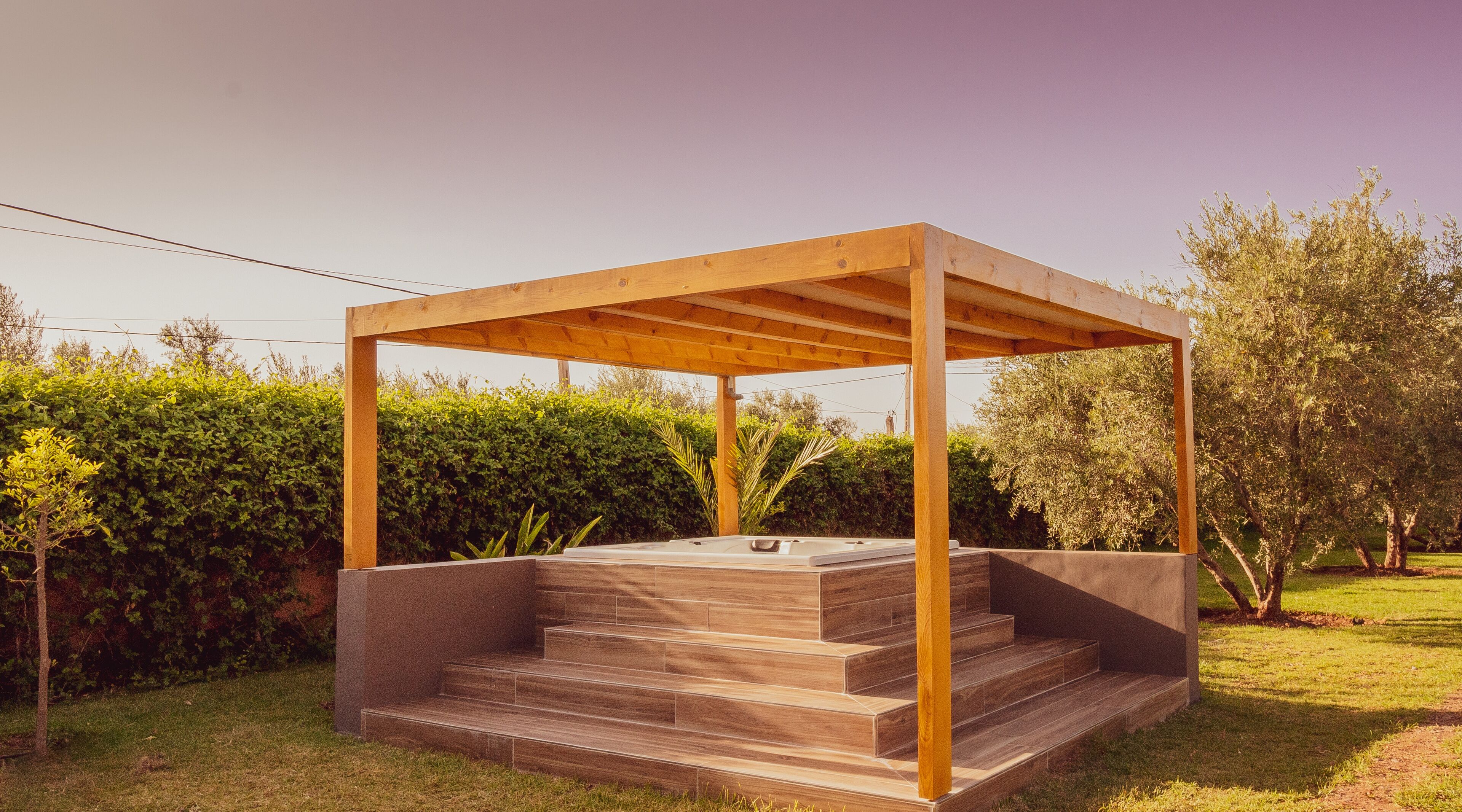 Una pérgola de madera con un jacuzzi debajo.