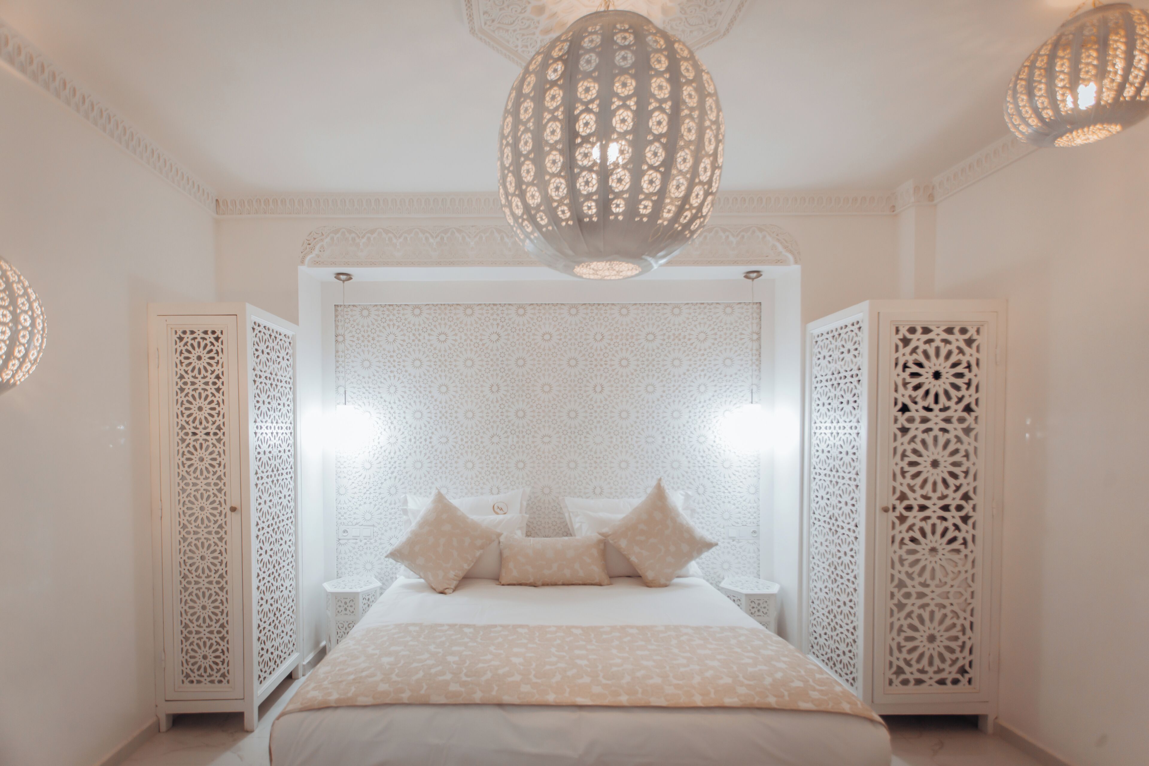 Une chambre dotée d’un grand lit, d’un luminaire décoratif au plafond et de panneaux muraux aux motifs complexes.