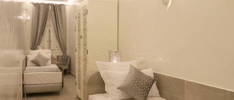 A bedroom with a bed, a chair, and a nightstand.