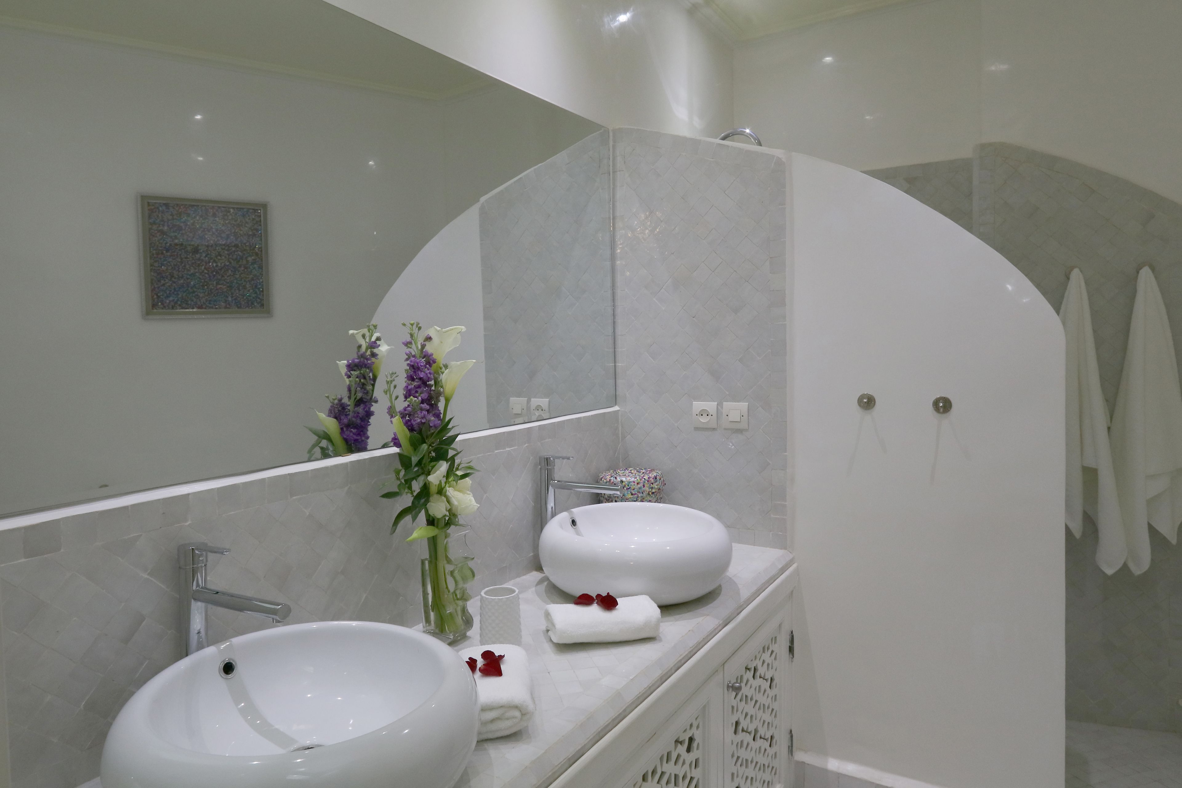 A modern bathroom with two sinks, a large mirror, and a shower area.