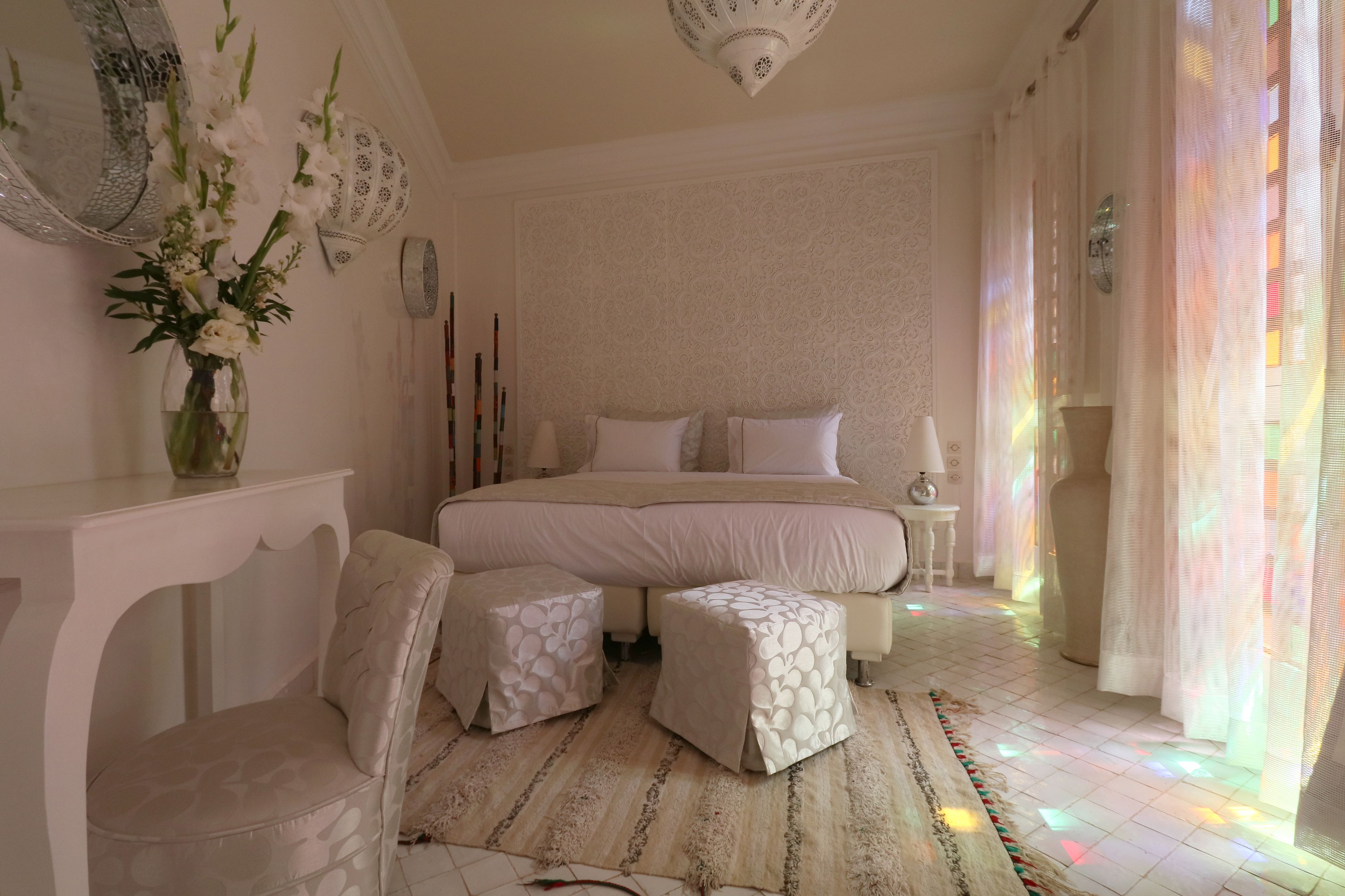 Un dormitorio con una cama grande, dos mesitas de noche, una silla y una pequeña mesa.