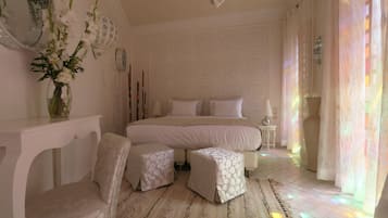Un dormitorio con una cama grande, dos mesitas de noche, una silla y una pequeña mesa.