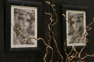 Dos fotografías en blanco y negro enmarcadas, con una rama decorativa al frente.
