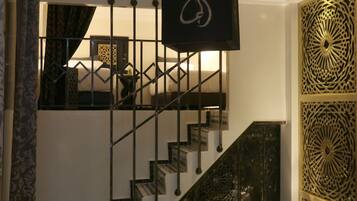 A staircase with a geometric railing design, a patterned wall panel, and a hanging light fixture.