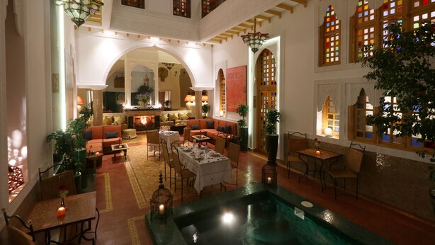 A spacious lobby with a seating area, a pool, and a staircase leading to an upper level.