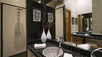 A modern bathroom with a black and white tiled sink, a shower, and a large mirror.