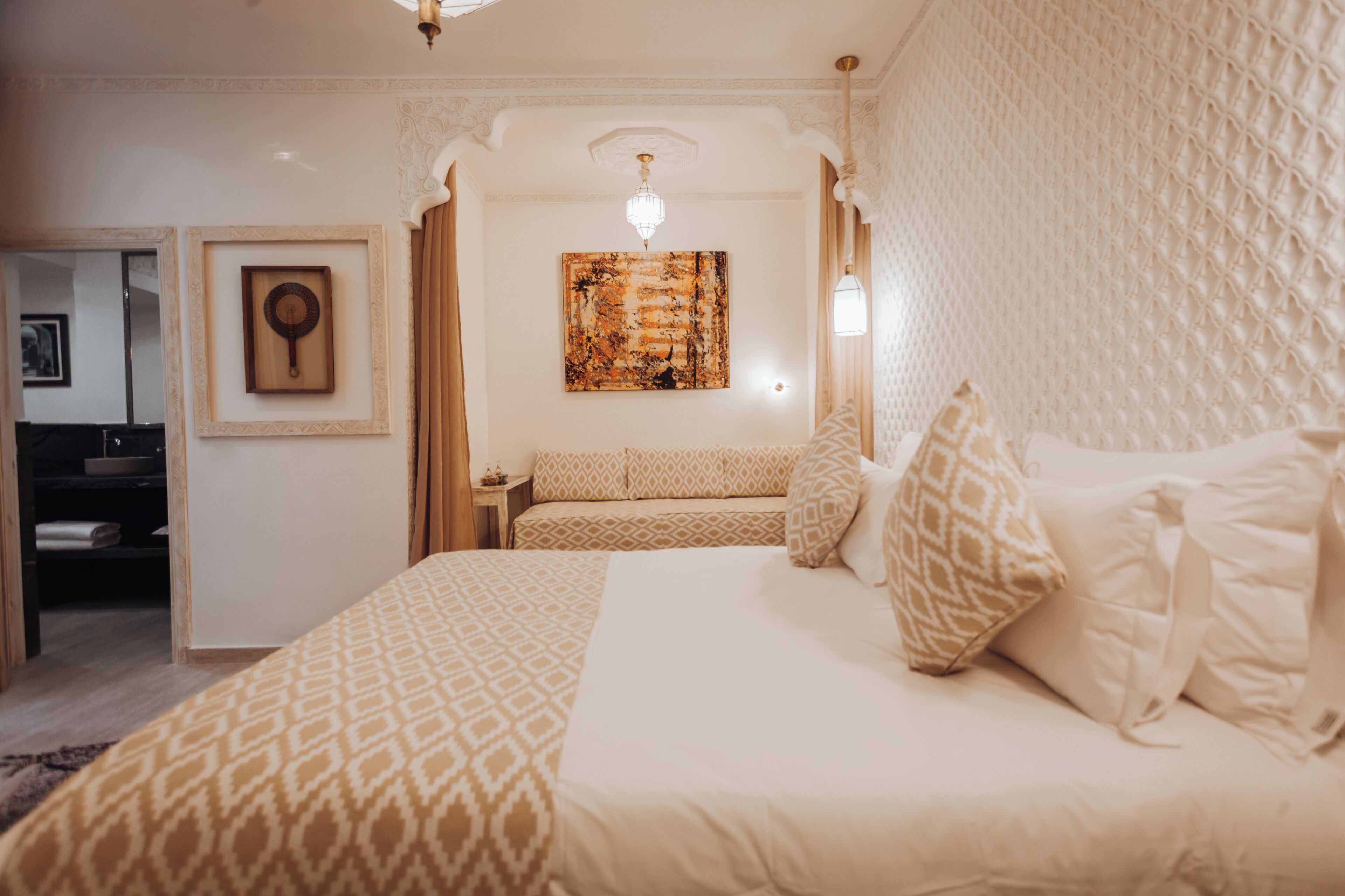 Une chambre d’hôtel avec un grand lit, une table de chevet, une œuvre d’art accrochée au mur et une porte donnant sur une salle de bain.