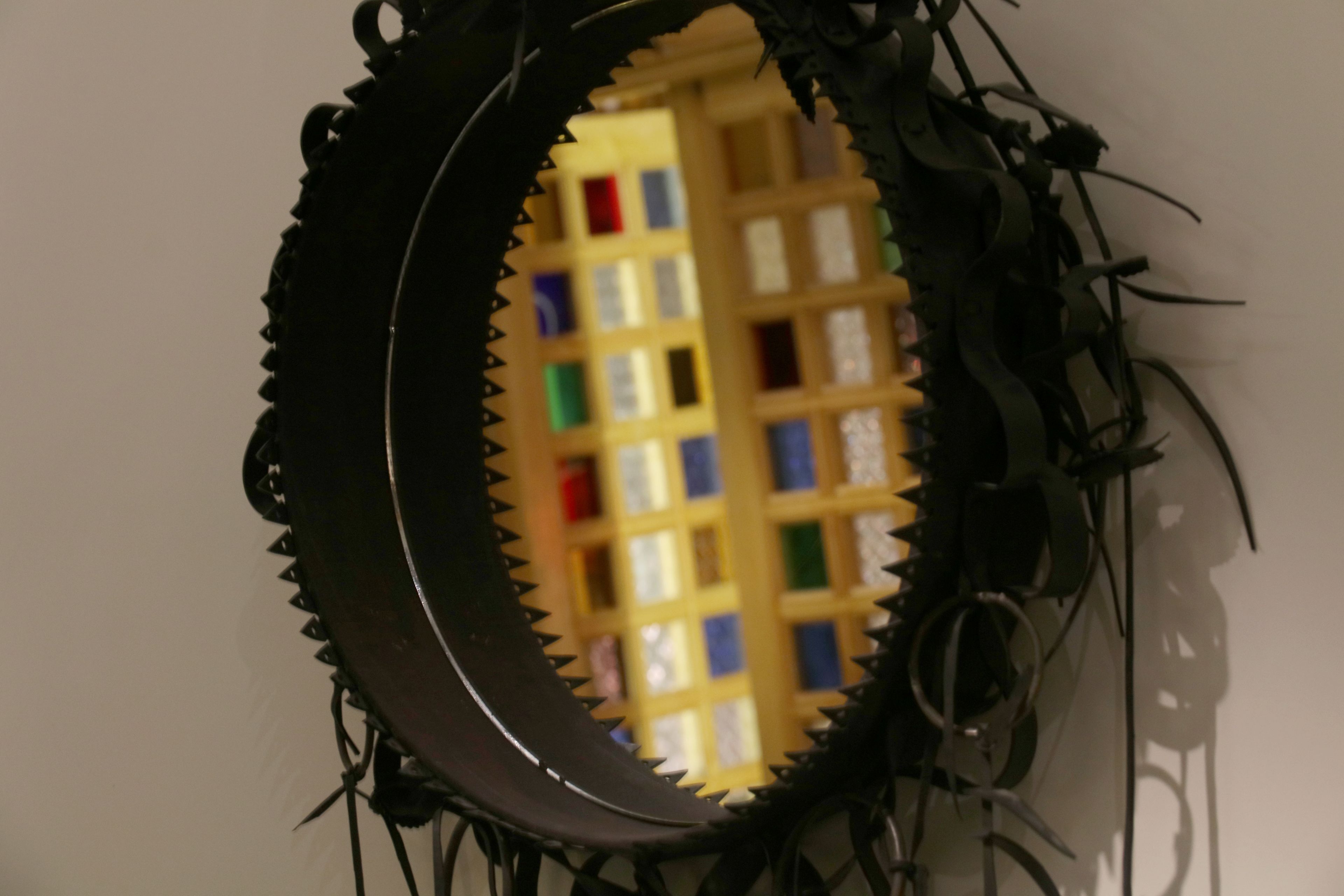 A circular mirror with a serrated edge, reflecting a building with colorful windows.