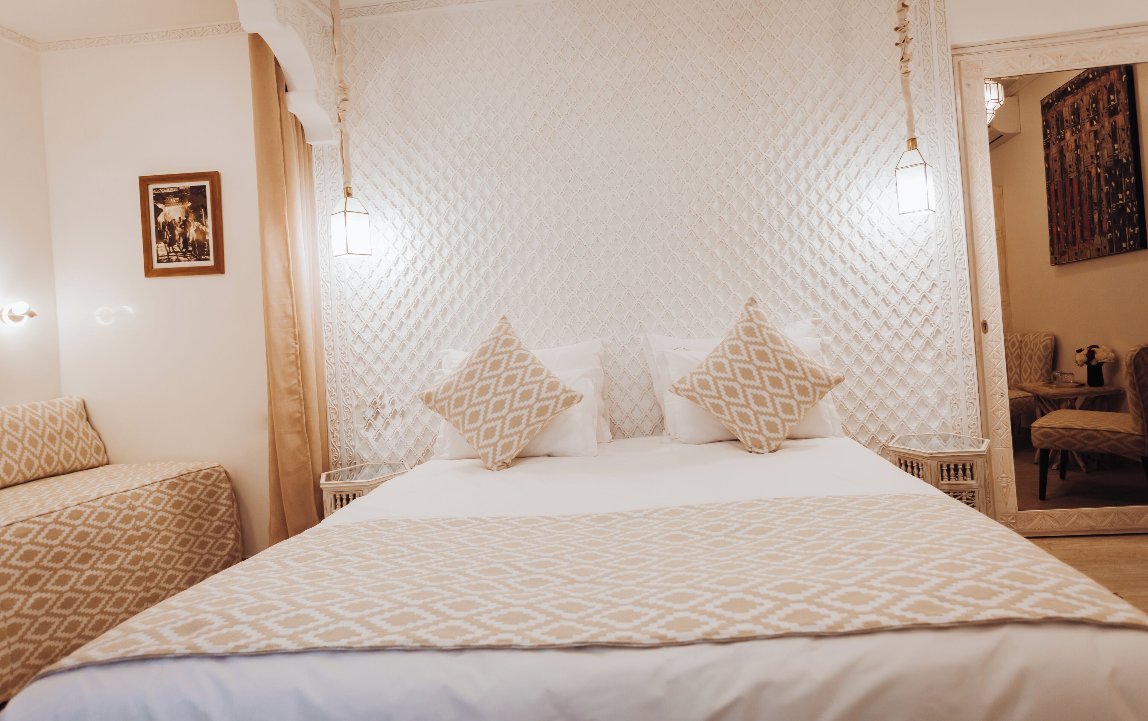 Une chambre à coucher avec un lit à baldaquin, des coussins à motifs et un miroir décoratif.