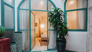 A room with a bed, a potted plant, and a patterned floor.