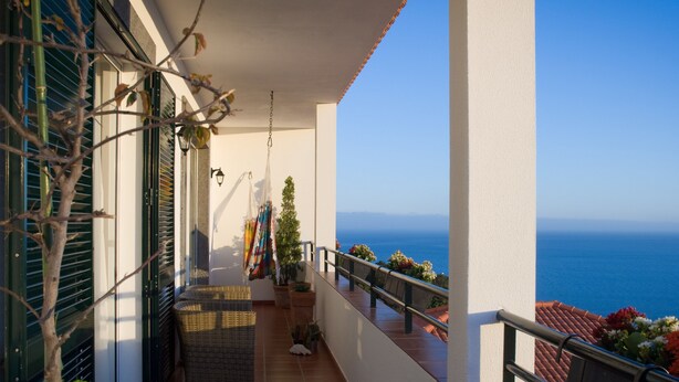 Balkon med havudsigt, en hængekøjsstol og plantekrukker.