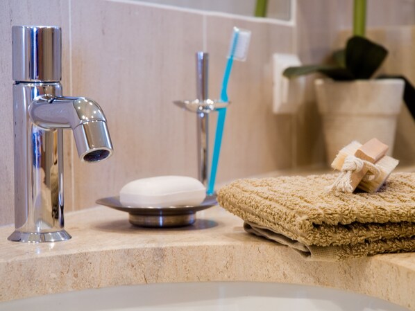 A bathroom sink with a chrome faucet, a soap dish, a towel, and a toothbrush holder with a toothbrush. - Murteiras Apartment (Funchal)