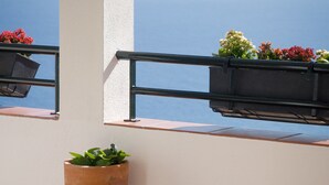 En balkon med plantekasser og havudsigt.
