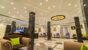 A hotel lobby with a reception desk, seating area, and a large clock.