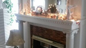 A room with a fireplace, a mirror above it, and a small table with a lamp.