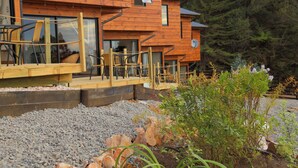 A wooden cabin with outdoor seating and a gravel pathway. - Cabañas y Spa Costa Patagonia (Pichilemu)