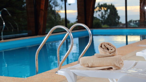 A poolside area with a metal ladder, a white lounge chair, and a towel. - Cabañas y Spa Costa Patagonia (Pichilemu)