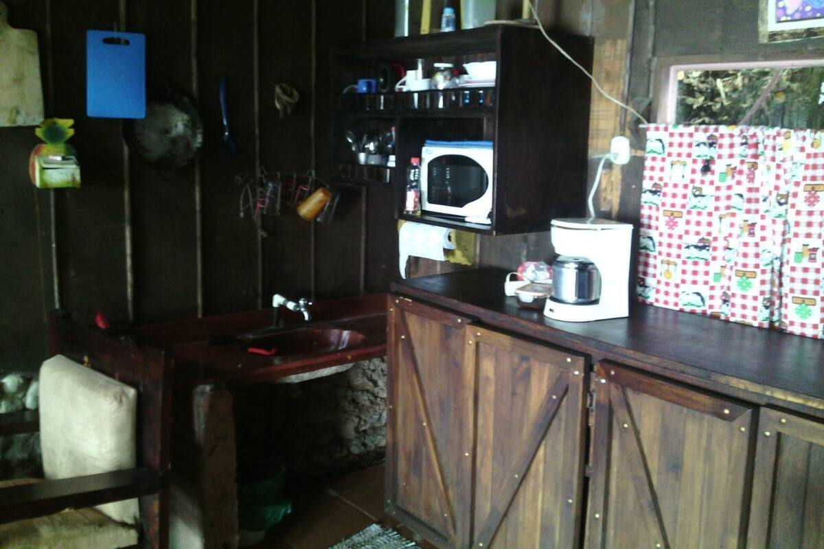 A rustic kitchen with wooden cabinets, a sink, a microwave, and a coffee maker.