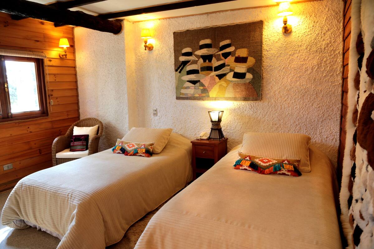 A cozy room with two beds, a window, and a wall-mounted artwork.
