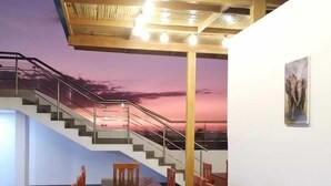 Un salón de conferencias con una mesa grande y sillas, una escalera y un mural con un atardecer en la pared.