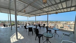 Una terraza al aire libre con varias mesas y sillas, que ofrece vistas a la ciudad y al mar.