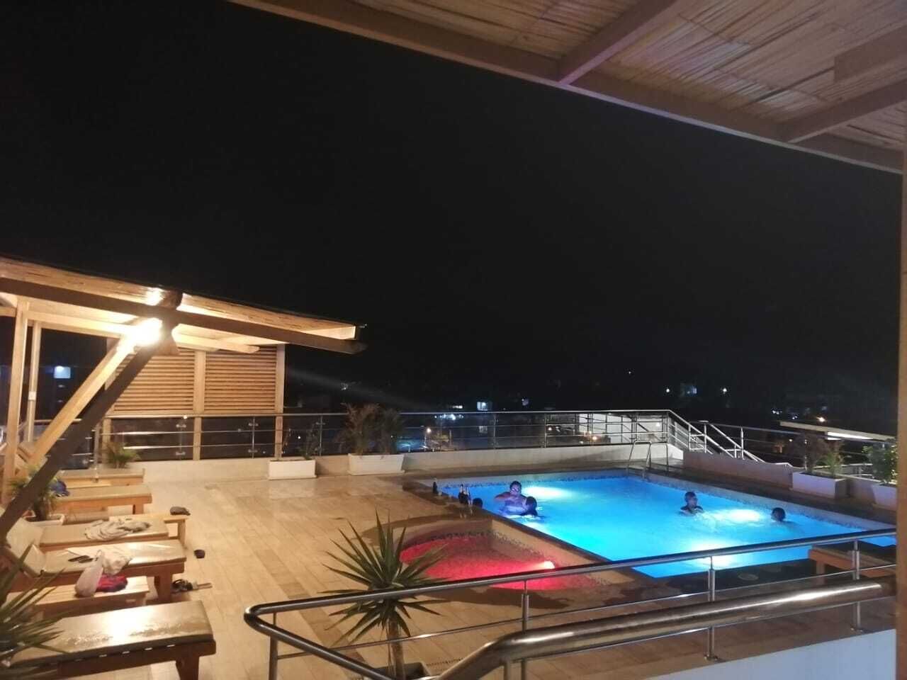 Ein Pool im Freien mit Holzterrasse und Liegestühlen, umgeben von einer Holzpergola und einem Geländer.