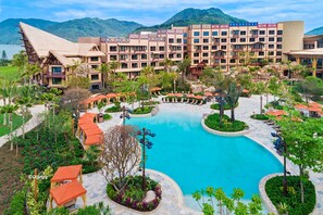 Un resort con piscina central, varias edificaciones y exuberante jardinería.