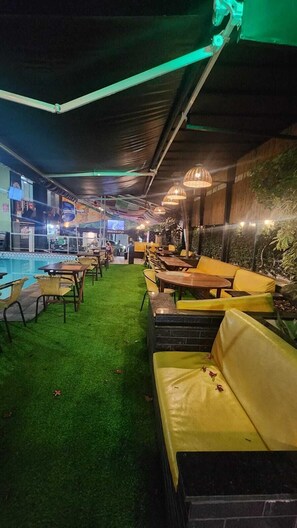 An indoor pool area with artificial grass, yellow and black seating, and hanging lights.