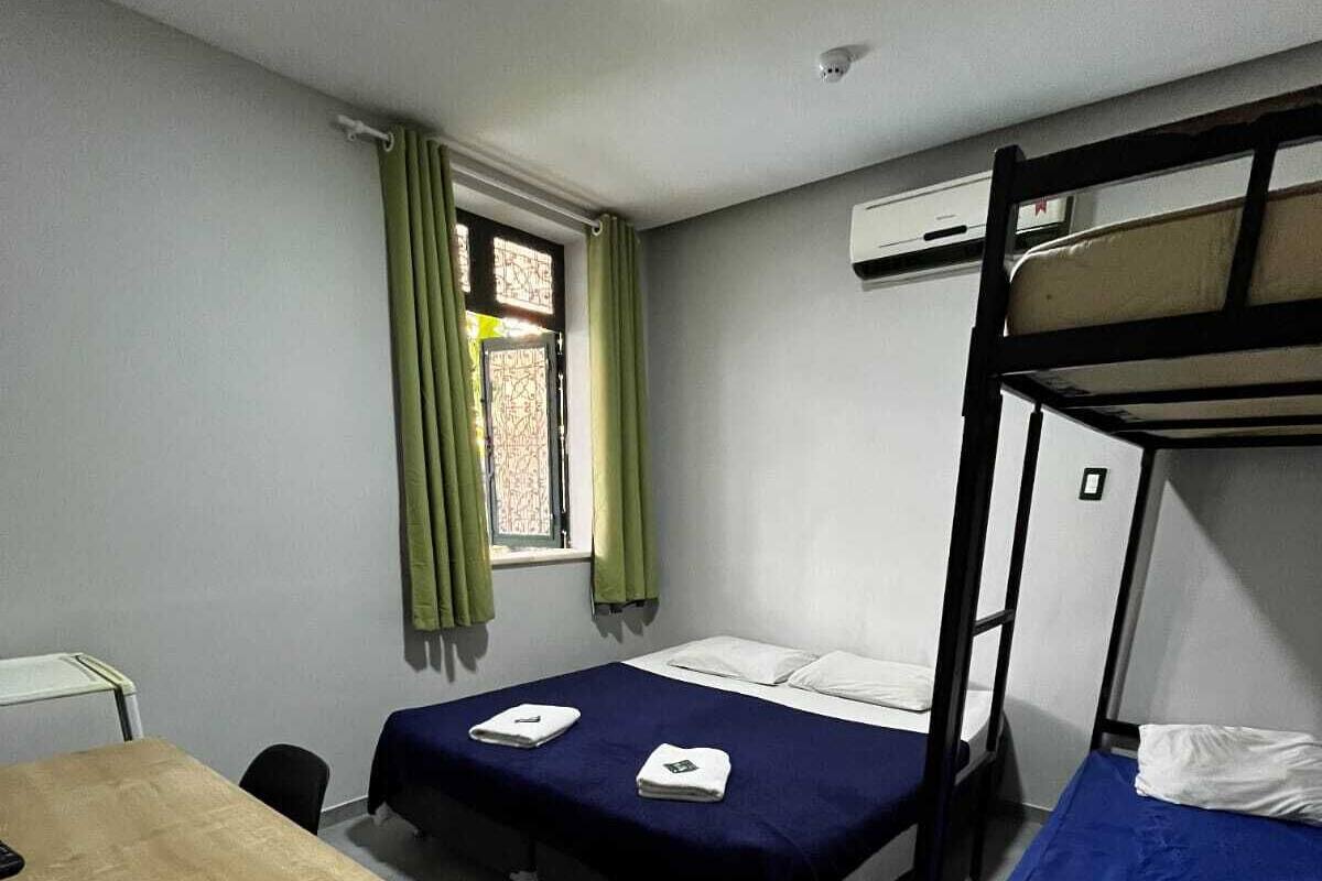 Un dormitorio con dos literas, una cama individual, una mesa de madera y una ventana con cortinas.