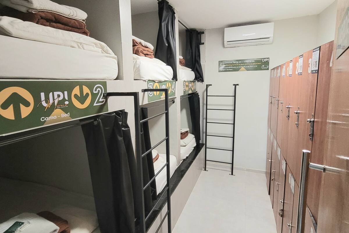 Habitación tipo dormitorio con literas, una escalera, varios taquillones y un cartel con el número de la habitación.