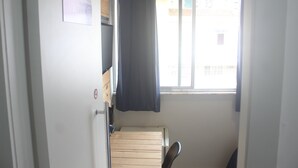 A narrow room with a window, a bed, and a chair. - Maraca Hostel (Rio de Janeiro)