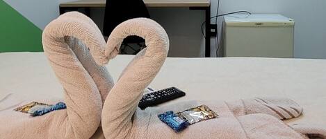A hotel room with a bed, a TV mounted on the wall, a desk, and a chair.
