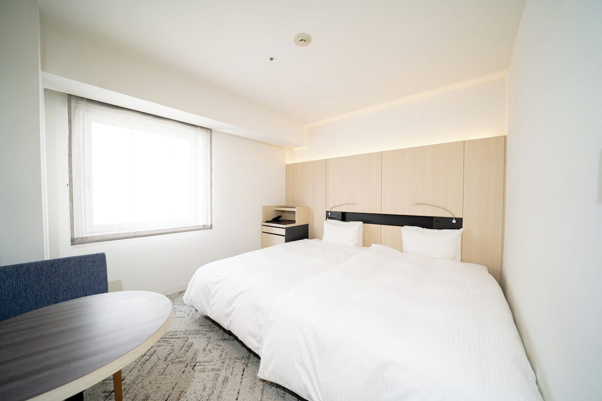 A modern hotel room with a large bed, a desk, and a chair.