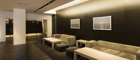 A modern interior with a sofa, ottoman, and tables arranged in a lounge area.