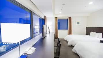Habitación de hotel con dos camas, un escritorio con teléfono, un ventanal grande y vistas a la ciudad.