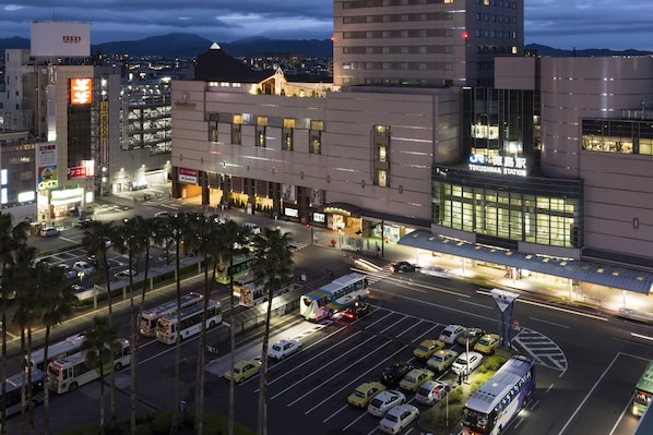 A modern building with a large glass facade, a prominent entrance, and a parking area with multiple vehicles.