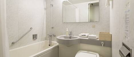 A modern bathroom with a bathtub, a toilet, a sink, and a mirror.