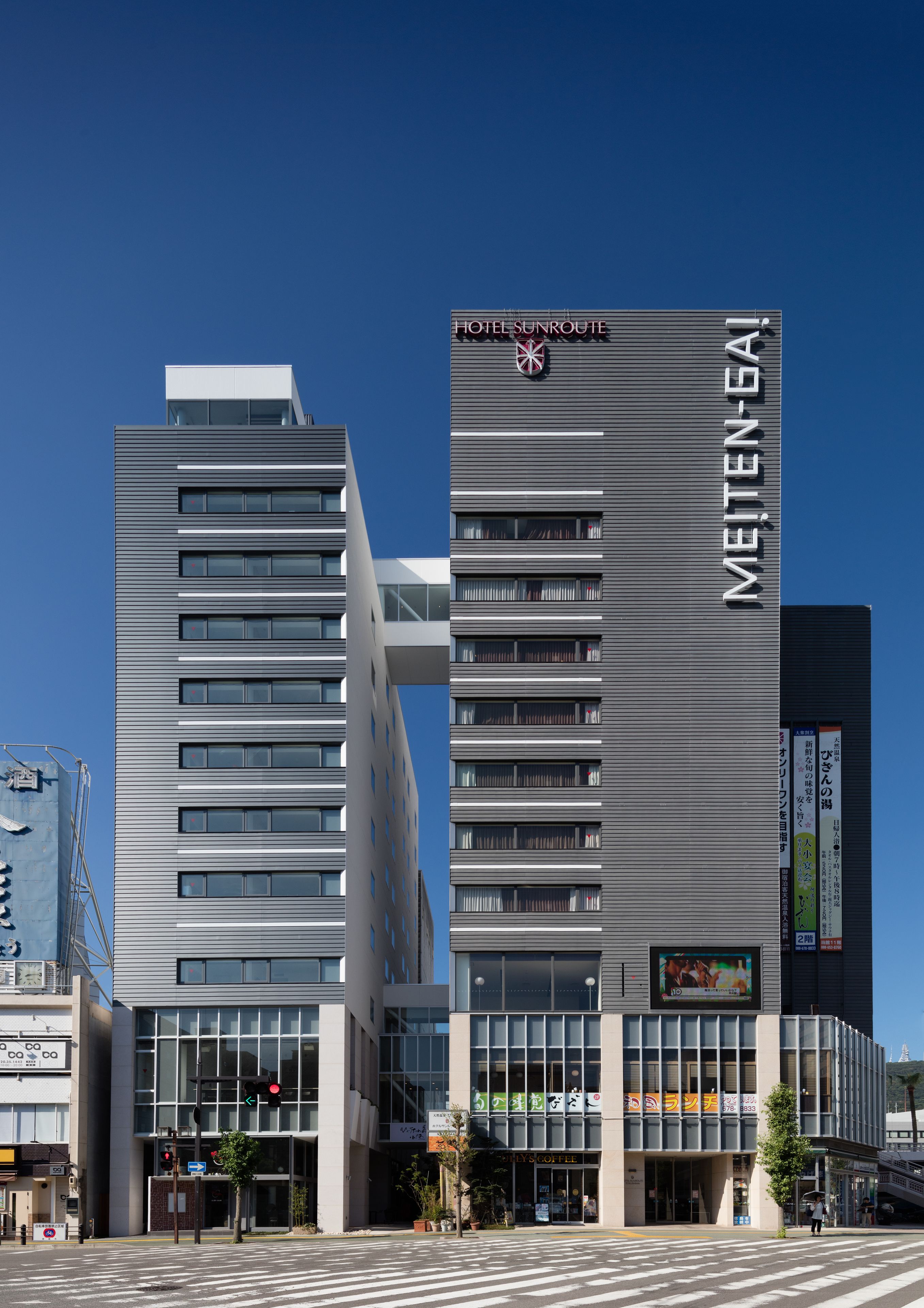 A modern hotel with a prominent sign reading "HOTEL SUNROUTE MEITETSU-GAI".