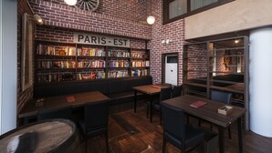 A cozy reading area with bookshelves, tables, and a sign reading "PARIS-EST". - Hotel Sunroute Tokushima (Tokushima)