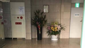 Un hall d’hôtel comprenant un comptoir d’accueil, un panneau indiquant le guichet d’enregistrement, un extincteur et une porte portant l’inscription « Entrée ».