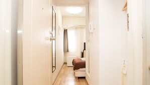 Un couloir étroit, avec un lit et un radiateur au fond.