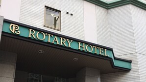 L’extérieur de l’hôtel Rotary, avec une entrée verte et un distributeur automatique situé à droite.
