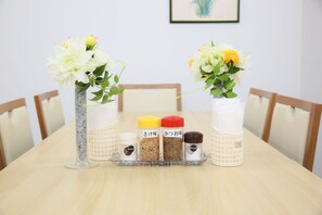 A table with two vases of flowers and three spice containers. - Rotary Hotel Imazato (Osaka)