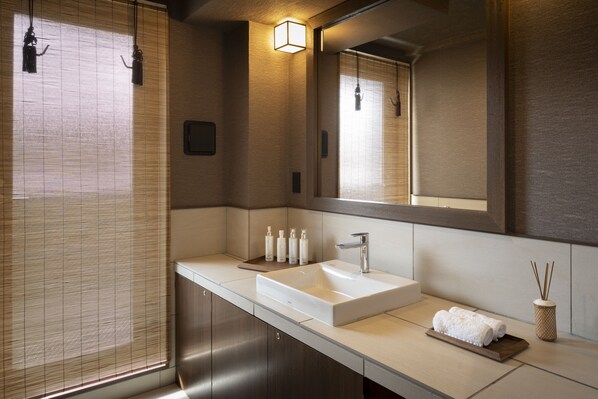 A modern bathroom with a large mirror, a white sink, and a wooden tray.