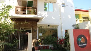 A two-story building with a visible entrance, a balcony, and several potted plants. - Giecel Pension (El Nido)