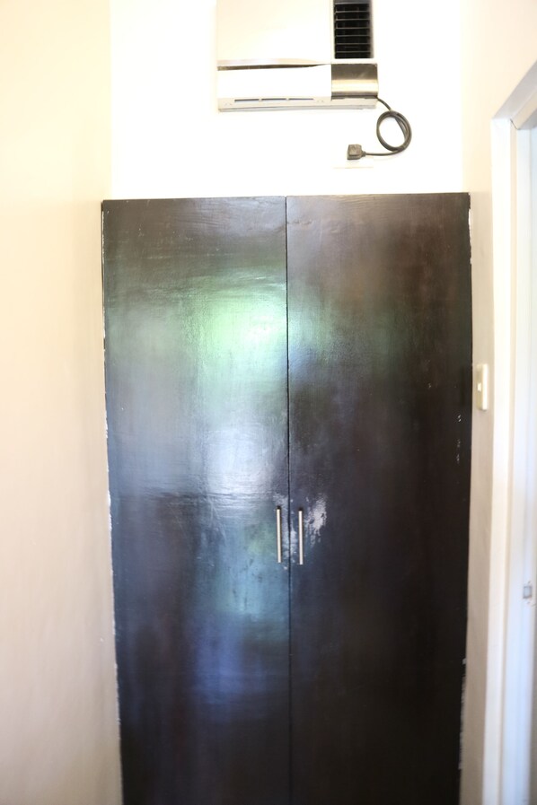 A black wardrobe with two doors and a small window at the top. - Giecel Pension (El Nido)