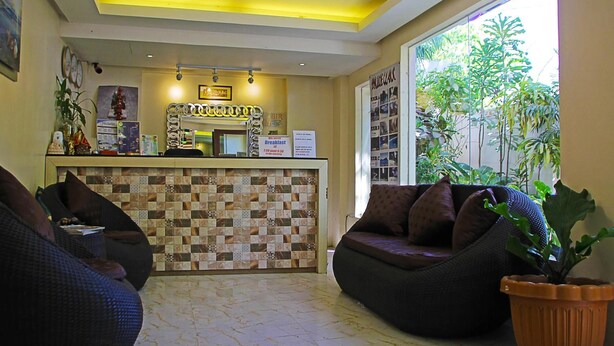 A reception area with a check-in counter, seating area, and a view of greenery outside. - Giecel Pension (El Nido)