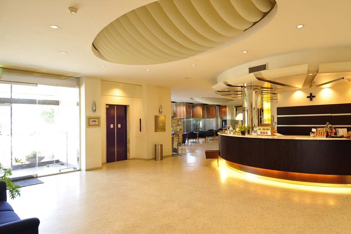Eine moderne Hotelhalle mit Empfangsschalter, einer Sitzecke und einem großen Fenster.